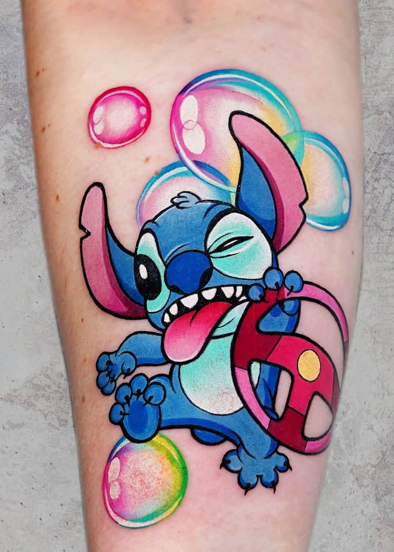 Tatuaż Żywy tatuaż bajkowy Stitcha z filmu Disneya „Lilo i Stitch” na przedramieniu przedstawia podekscytowanego Stitcha, trzymającego kierownicę z wysuniętym liderem i połączonym jednym okiem. Otoczone kolorowymi bąbelkami, ten zabawny wzór jest idealny dla fanów czytających tatuaży!